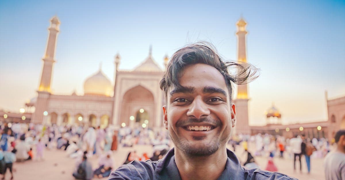Smiling tourist taking a selfie at Old Delhi's Jama Masjid during sunset, capturing Mughal architecture