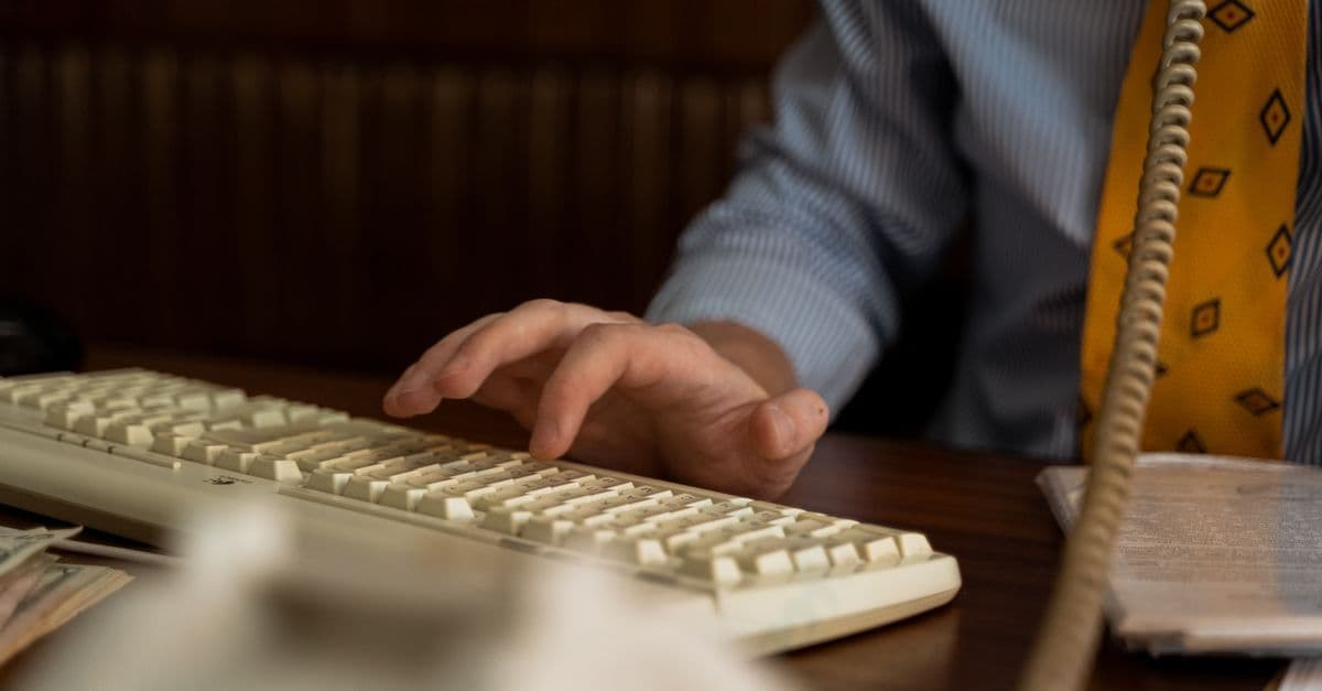 Man in business attire typing on a vintage keyboard during the dial-up internet cafe era