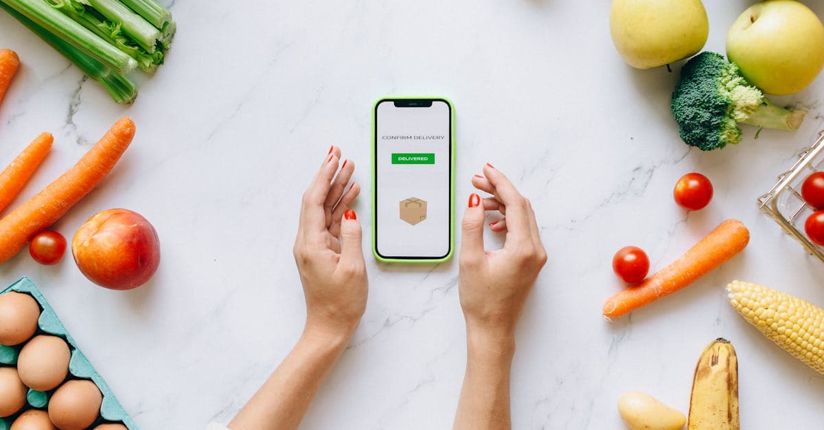 Hände halten ein Smartphone mit Online-Bestellung für gesundes Essen, umgeben von frischem Obst und Gemüse.