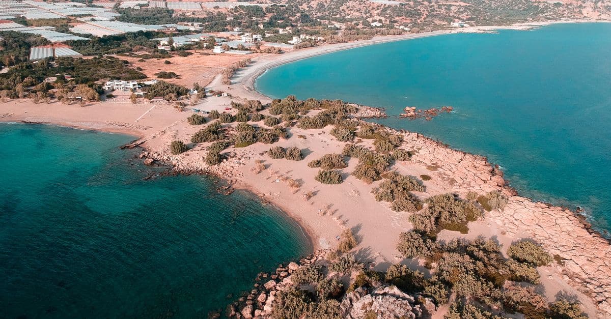 Türkisfarbene Bucht mit Sandstrand an der griechischen Mittelmeerküste zur optimalen Reisezeit beim Griechenland Urlaub