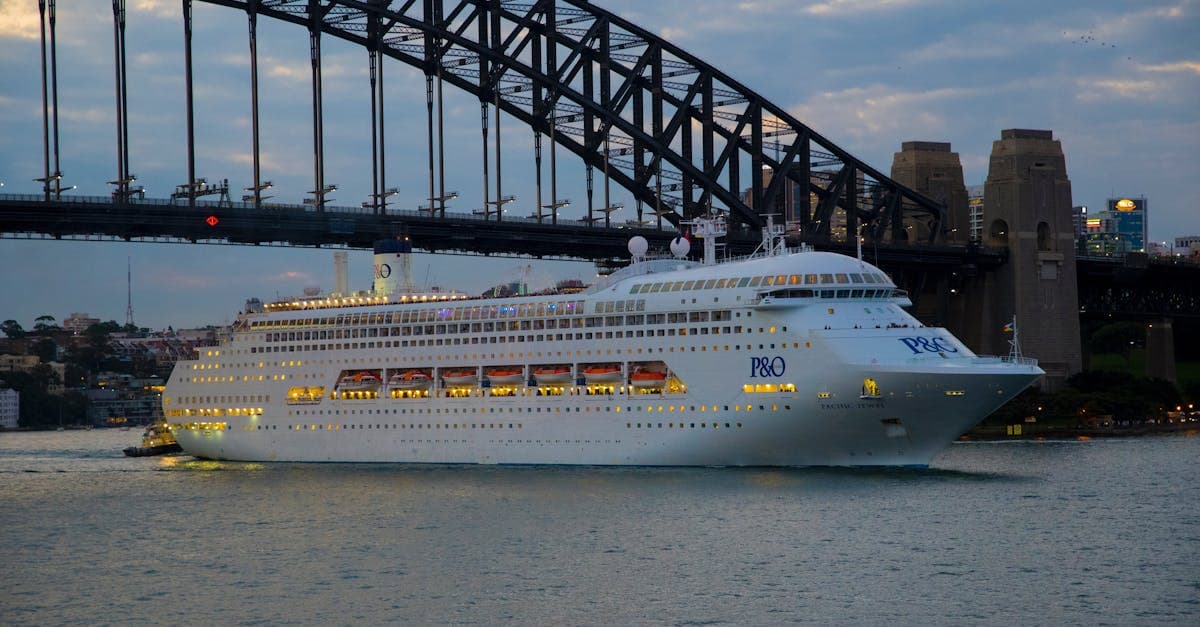 Elegant cruise ship navigating under Sydney Harbour Bridge at twilight on the New Zealand cruise route.