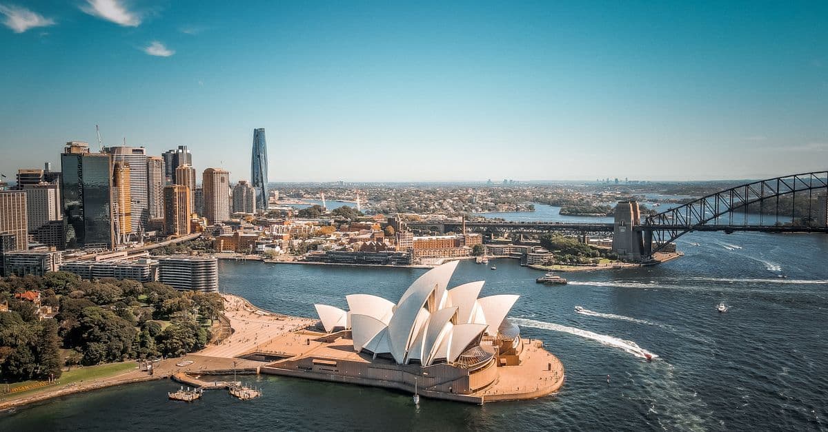 Vista aerea del Teatro dell'Opera di Sydney con l'Harbour Bridge, icona dell'Australia per chi cerca esperienze di vacanza lavoro.