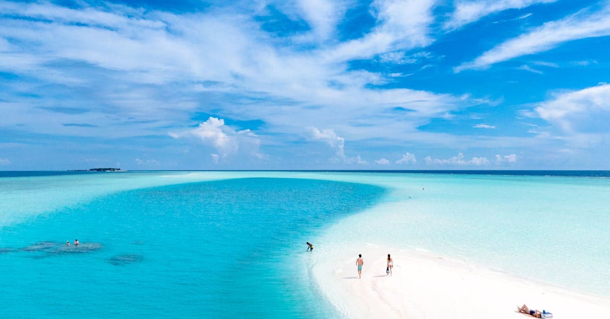 Turquoise Maldives beach with swimmers enjoying the cheapest months to visit maldives on a budget