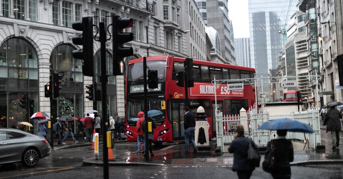 Pedestrians with umbrellas and red double-decker buses on a rainy London street, questioning london weather rainfall expectations