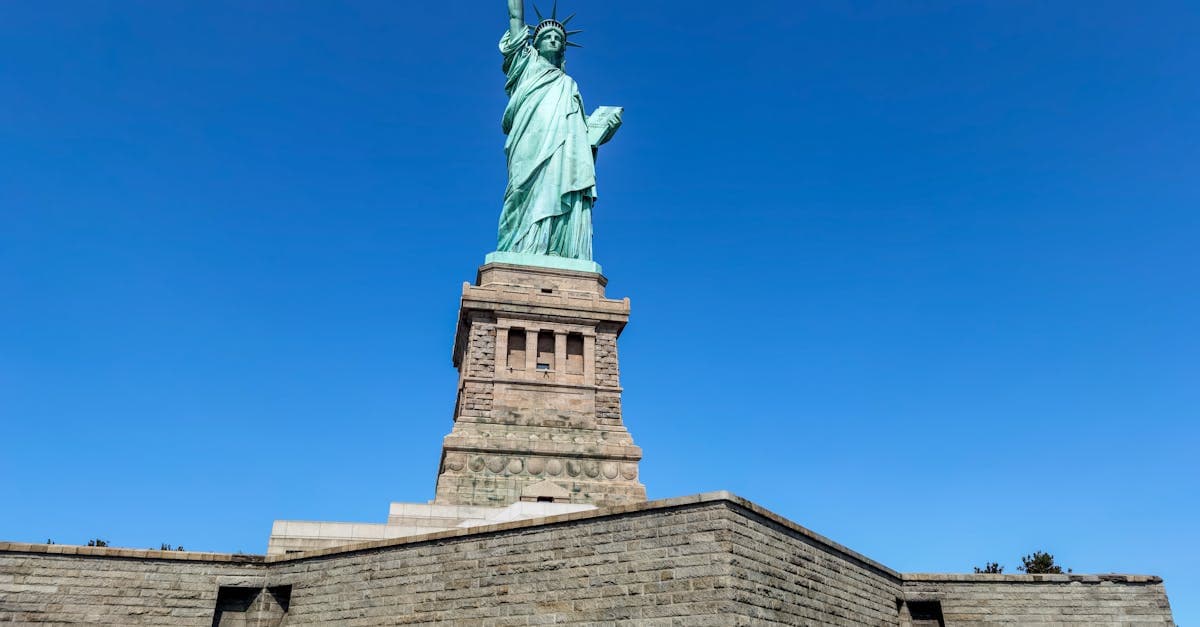 Low angle shot of the iconic Statue of Liberty against a clear blue sky in New York City.