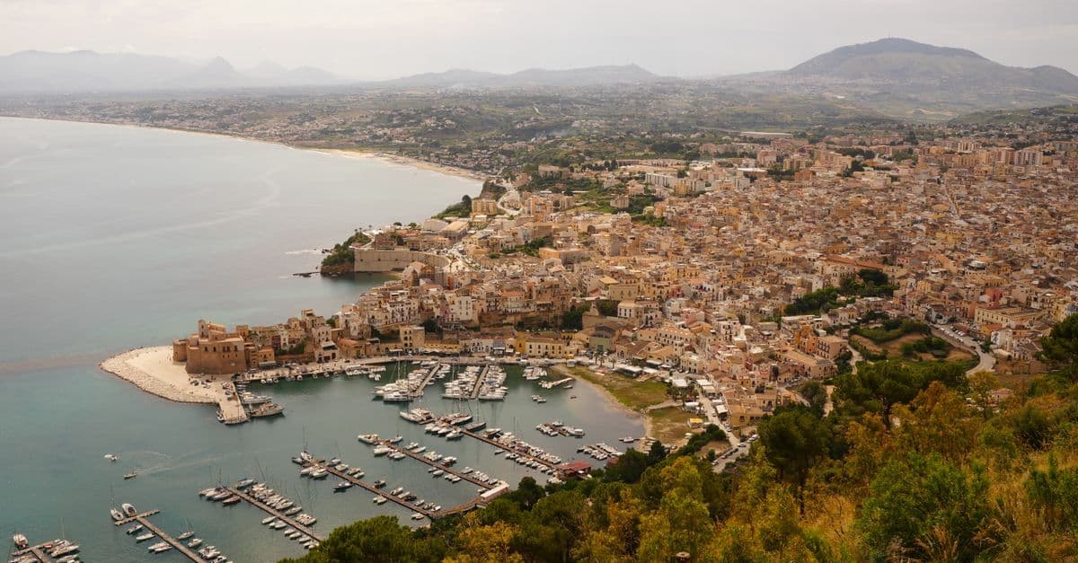 Vista aerea della costa e del porto di Castellammare del Golfo in Sicilia, meta lontana dalle rotte ferroviarie.