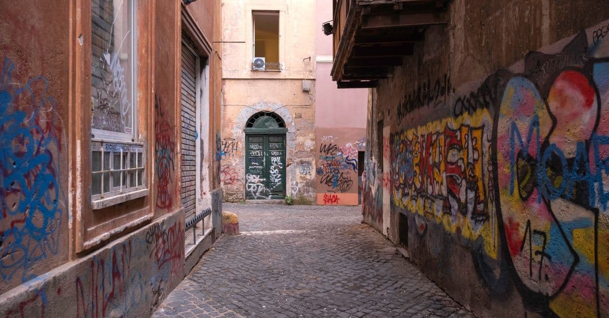 Narrow cobblestone alleyway adorned with colourful street art in one of Rome's hidden neighbourhoods