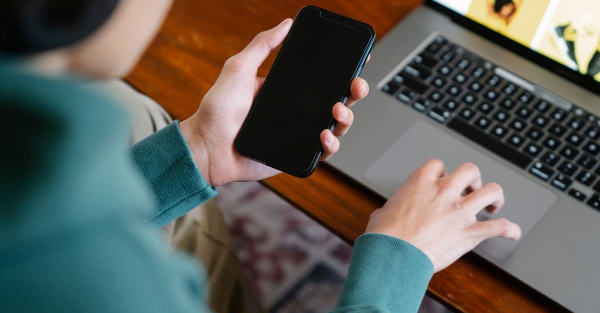 Persona che utilizza smartphone e laptop per lavorare da remoto con internet casa a 10 euro al mese.
