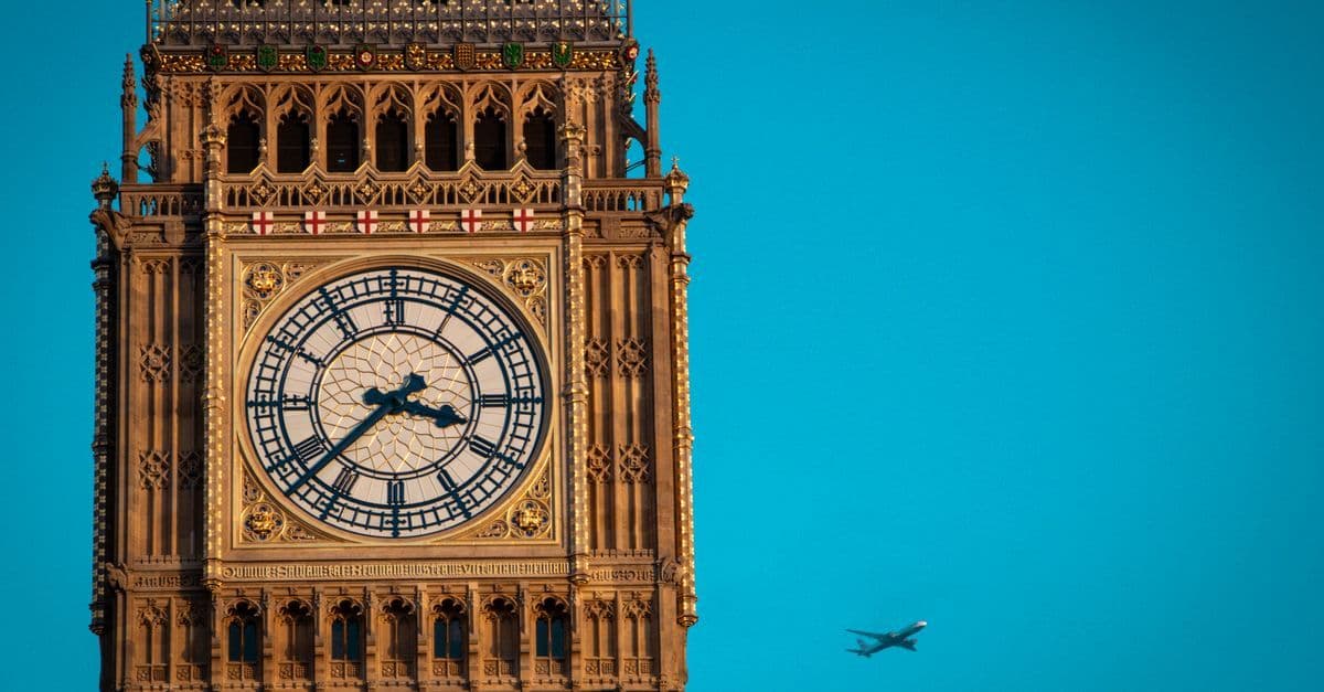 Torre del reloj Big Ben bajo un cielo despejado con un avión sobrevolando en Londres