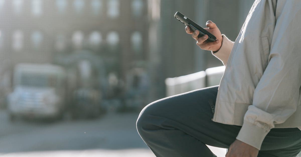 Man using mobile phone on city roadway to disable data roaming and avoid charges