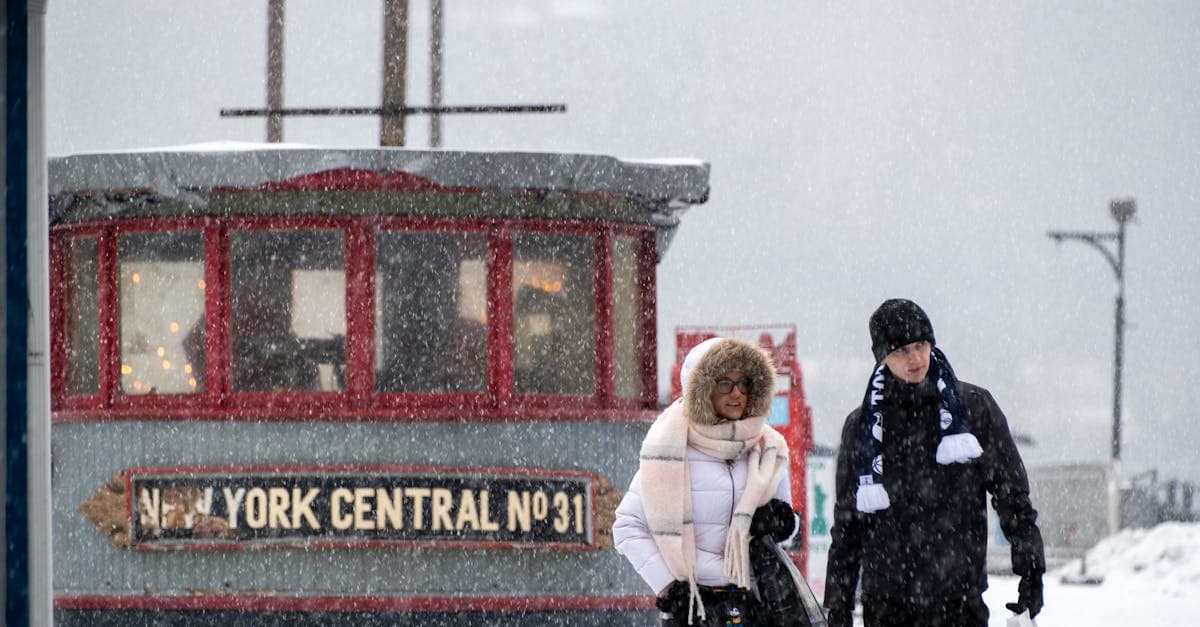Pedestrians bundled up walking through a heavy winter storm on a snowy New York street.