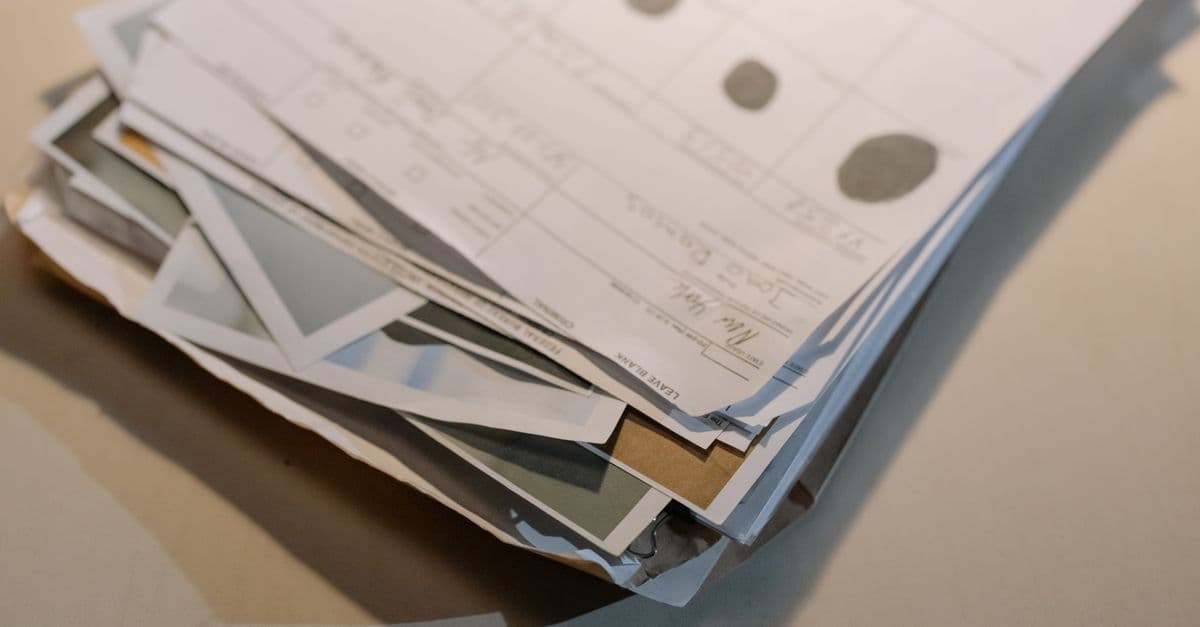 A stack of official-looking forms and documents, with parts of several photographs visible.