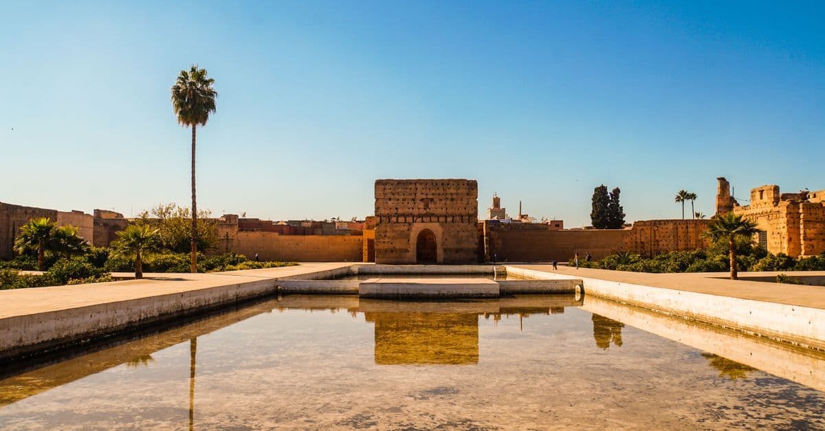 Palacio El Badi reflejado en su estanque bajo un cielo azul, ejemplo del buen tiempo en Marrakech