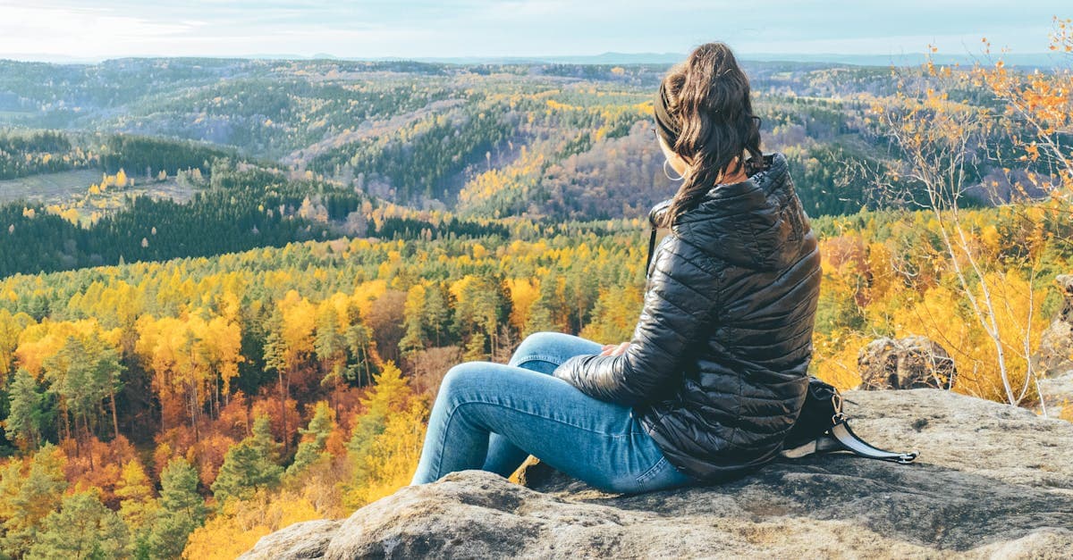 Frau genießt herbstliche Aussicht in der Sächsischen Schweiz mit leuchtend bunten Wäldern und weiter Landschaft
