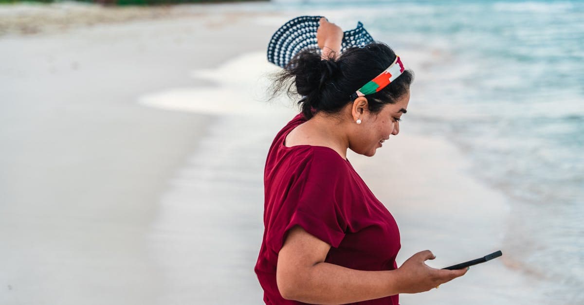 Frau am Strand prüft ihr Smartphone mit Meerblick – mit einer travel eSIM auf den Malediven vernetzt