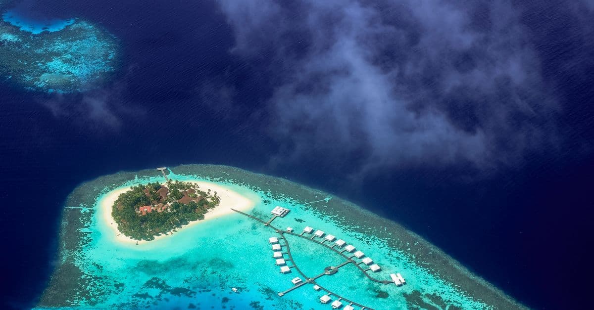Aerial view of a turquoise-ringed island resort, a sought-after destination for maldives holidays from the UK.