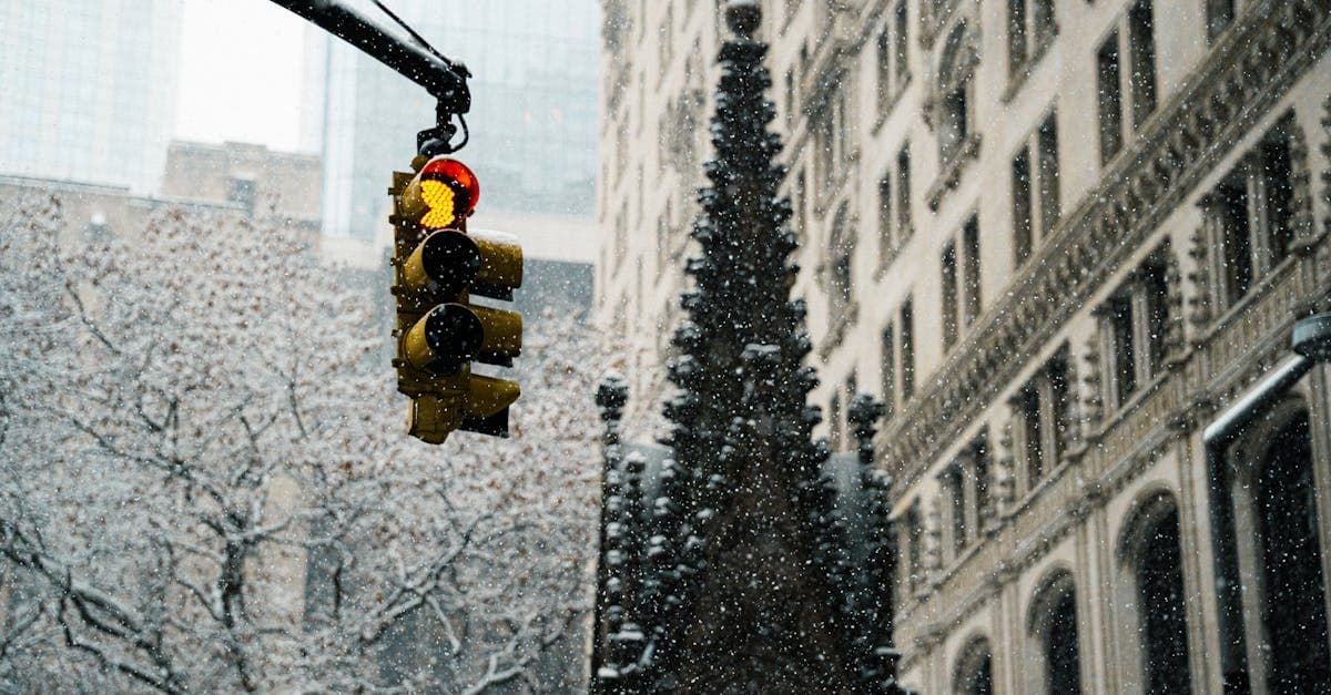 Red traffic light during a New York City snowfall framed by historic Manhattan architecture.
