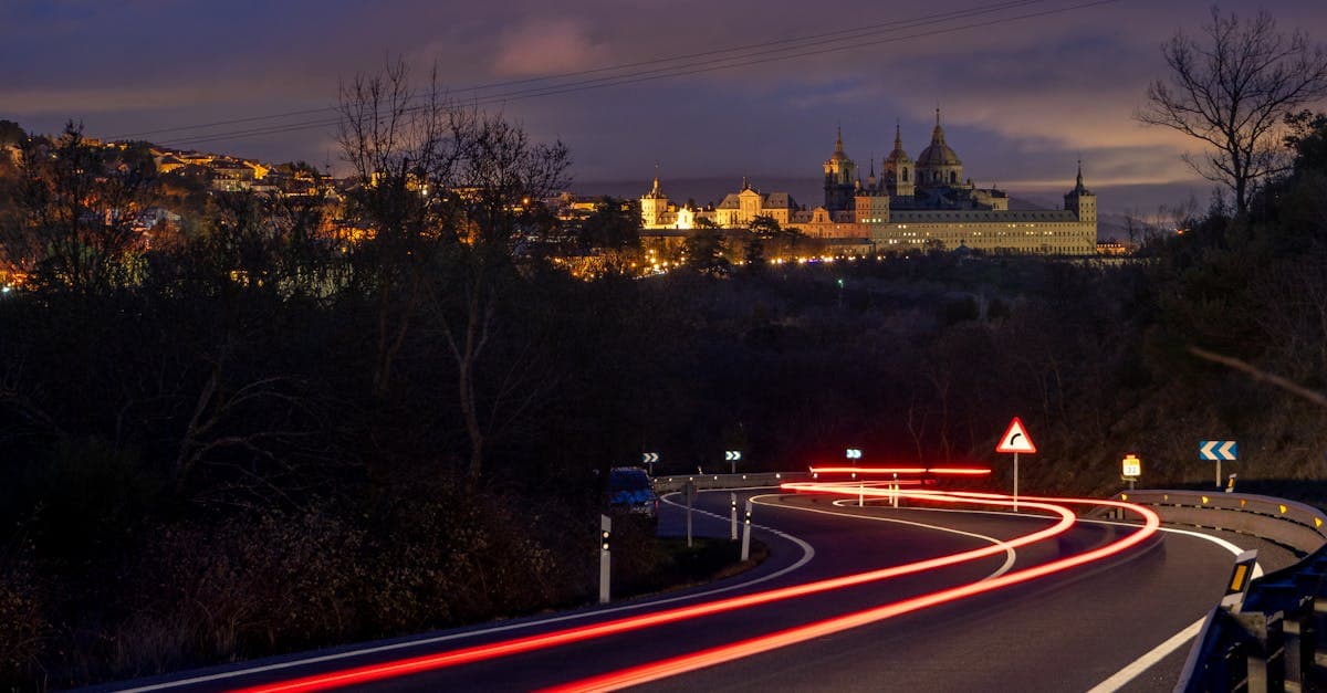 Vista nocturna de El Escorial con rastros de luz en carretera sinuosa, imagen del calendario MotoGP 2026