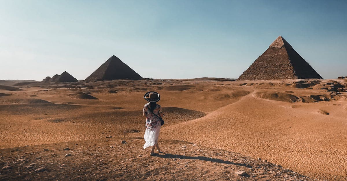 Kvinde står i den egyptiske ørken med pyramiderne i baggrunden på en rejse til Egypten