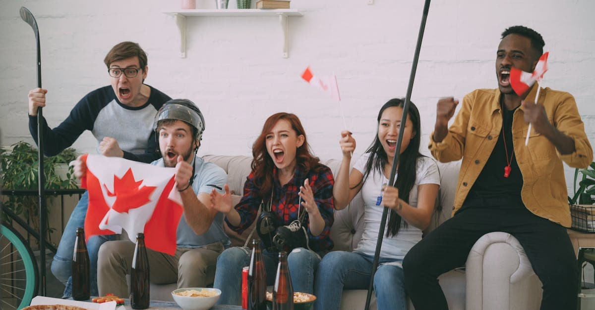 Diverse friends cheering for Canada with hockey gear, enjoying streameast app live sports together.![image