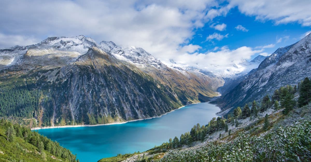 Türkisfarbener Bergsee inmitten schneebedeckter Tiroler Alpen – eines der beliebtesten Last-Minute-Reiseziele ab Österreich.