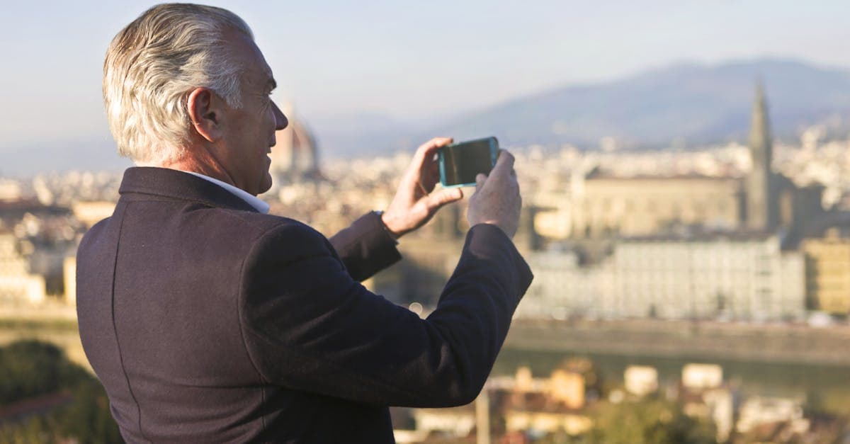 Senior traveler using a smartphone to stay connected while sightseeing on a sunny day abroad.