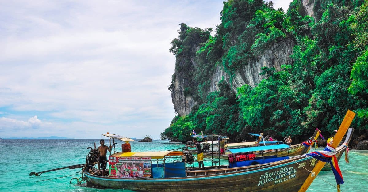 Traditional longtail boat in turquoise Phang Nga waters, a highlight of Thailand holiday packages.