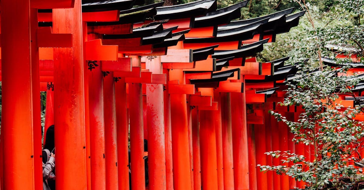 Vibrant red torii gates at Fushimi Inari Shrine surrounded by lush greenery in Kyoto, Japan