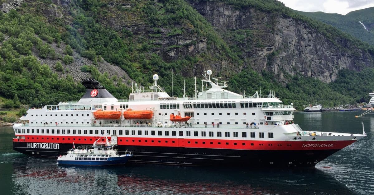 Large red and white cruise ship navigating the scenic fjords of Møre og Romsdal in Norway
