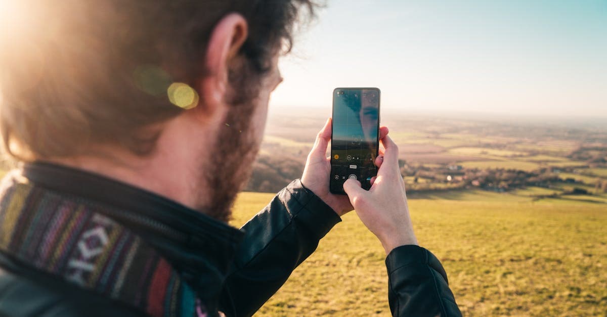 Man photographing a scenic Brighton coastal view on his smartphone, considering a travel eSIM for data abroad.
