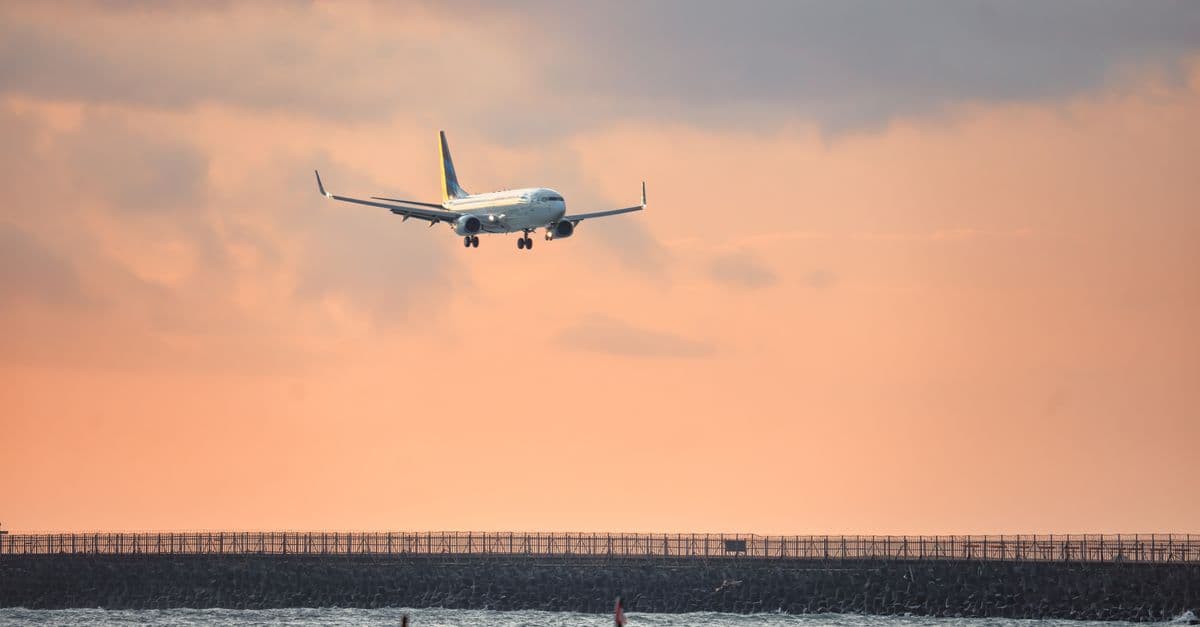 Plane descending towards Bali Airport at sunset, representing affordable flights to Bali year-round