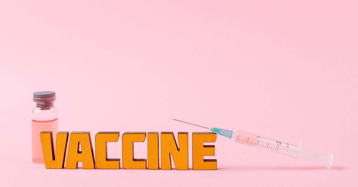 Seringue et flacon de vaccin sur fond rose représentant les vaccins recommandés comme l'hépatite A et la typhoïde.