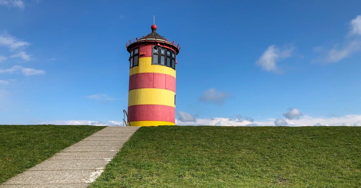 Pilsum Lighthouse with vibrant red and yellow stripes on a sunny day in Krummhörn, Germany.