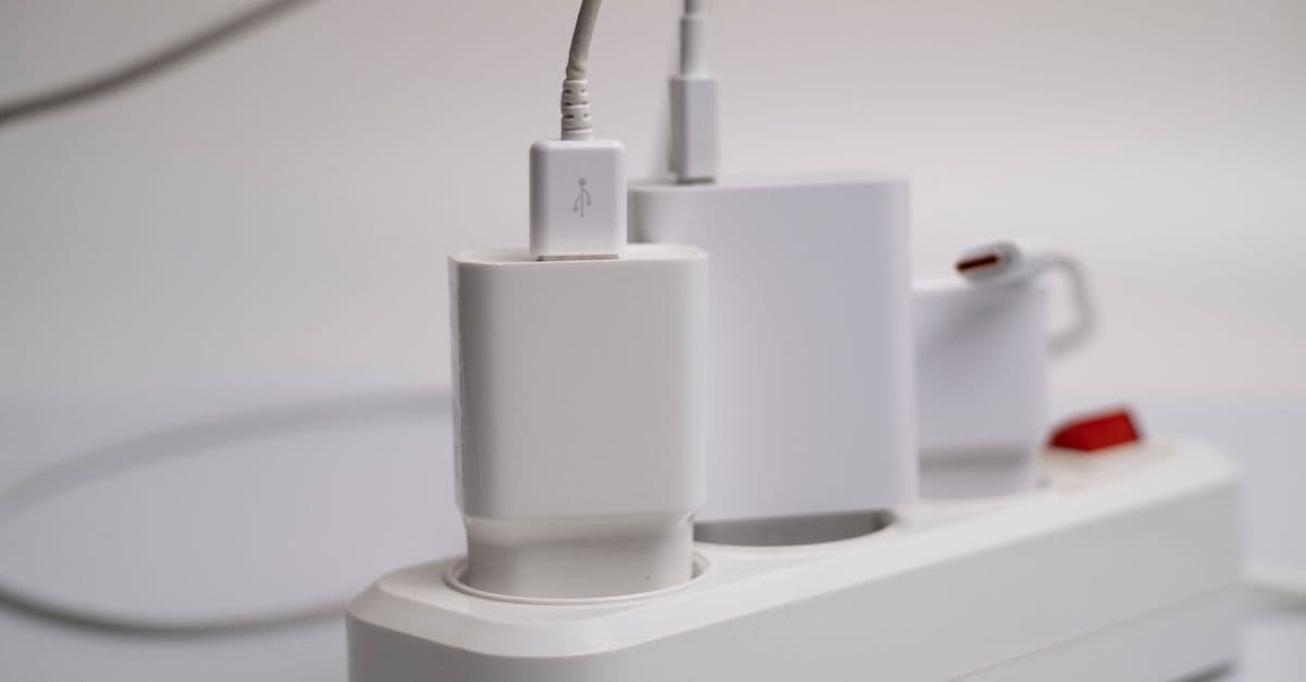 白いUSB充電器とアダプターが延長コードの差し込み口に並んで差し込まれている。