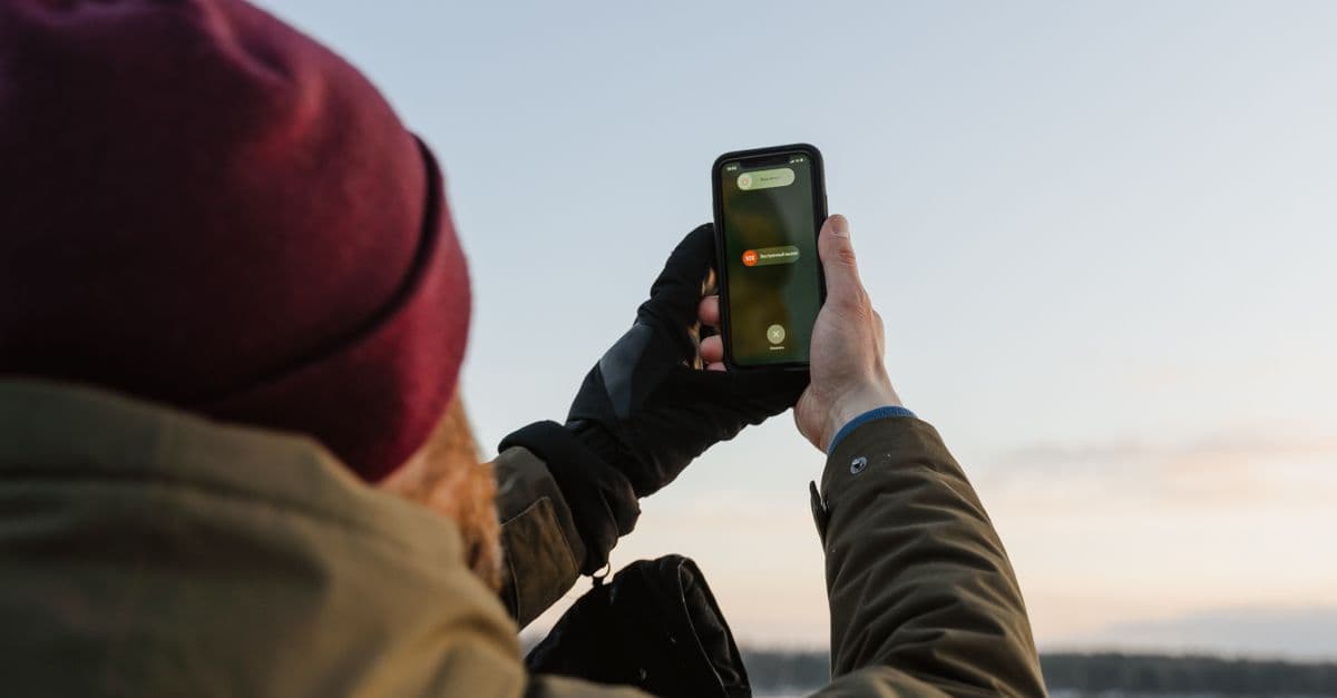 Mężczyzna korzystający ze smartfona na zewnątrz w zimowym krajobrazie, sprawdzający ofertę esim tmobile.