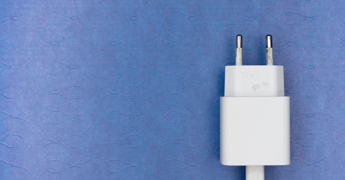 White electric charger plug on a blue textured surface, ideal for tech visuals.