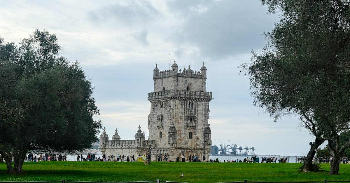 Que faire à Lisbonne : la Torre de Belém, monument historique entouré de verdure au bord du Tage.