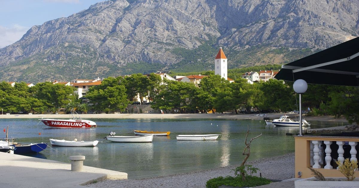 Idyllischer Blick auf Promajna mit Booten, ruhigem Wasser und majestätischen Bergen beim Kroatien Urlaub im Sommer.