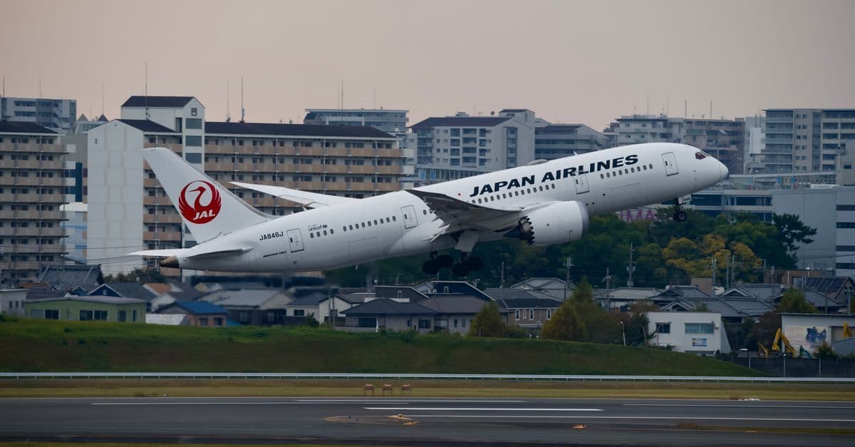 Japan Airlines Boeing 787 taking off from a bustling city airport on cheap flights to Japan.