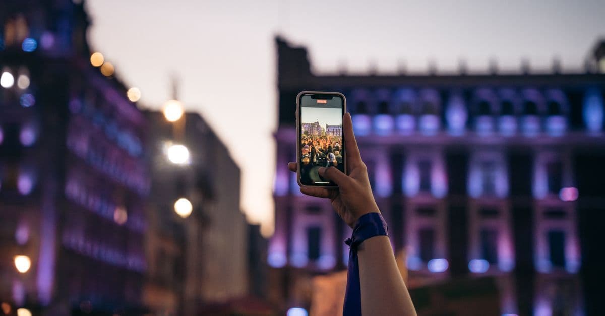 Travelers in illuminated Mexico City plaza at night using smartphones to manage travel eSIM and connectivity options.