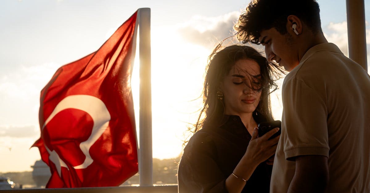 Couple enjoying a sunset cruise on the Bosphorus with a Turkish flag, highlighting affordable esim turkey roaming savings.