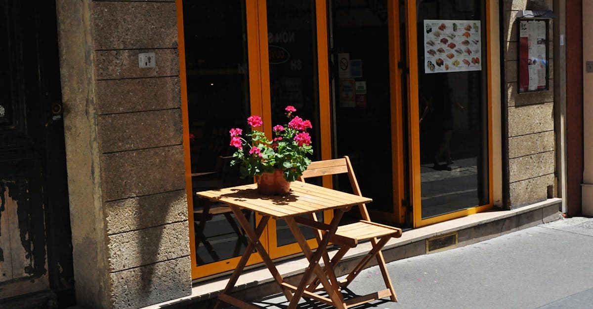 Mesa de madera soleada con flores en terraza romana, ambiente ideal para explorar los mejores restaurantes en Roma por barrios.