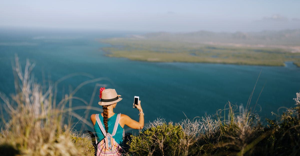 Viajera fotografiando el océano neblinoso desde un promontorio, pensando en la mejor conexión para su perfil de viaje