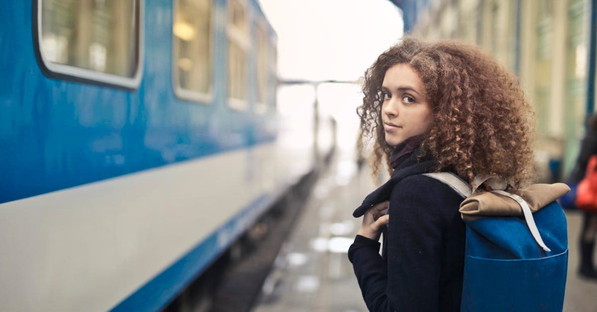 Young woman with a backpack waiting at a European train station while solo travelling abroad