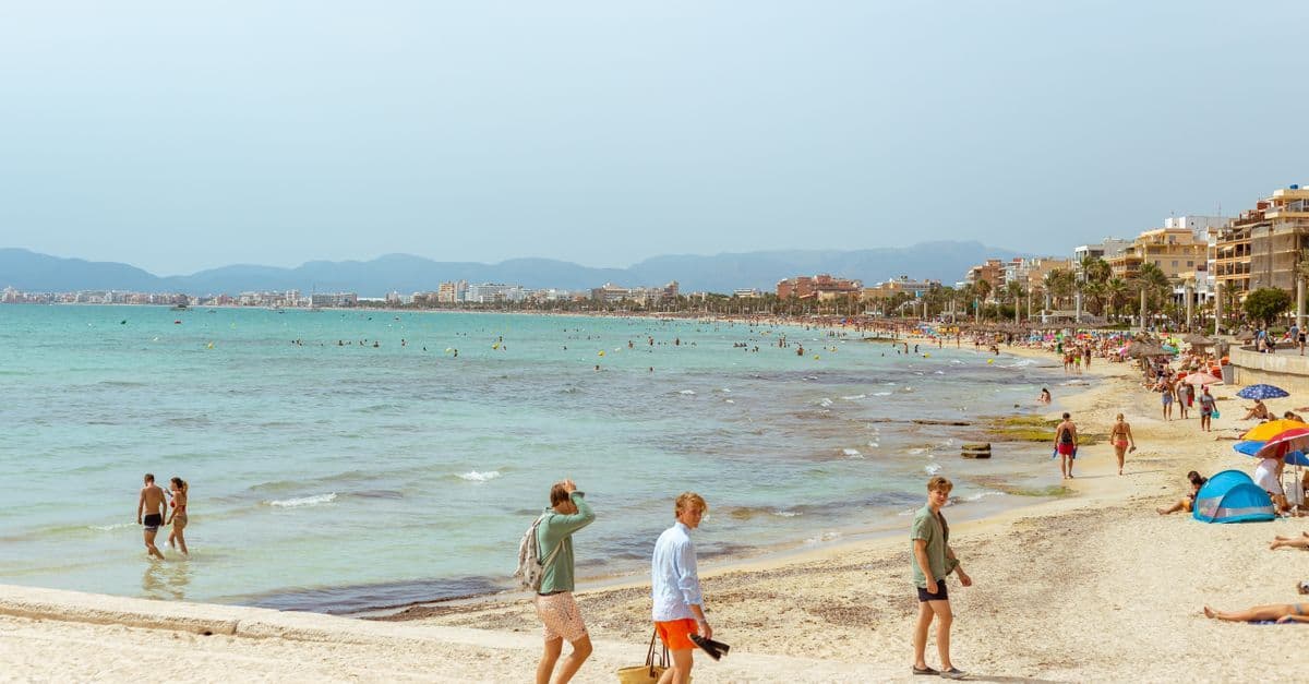 Badegæster nyder varmt mallorca vejr på en travl strand i april solskin