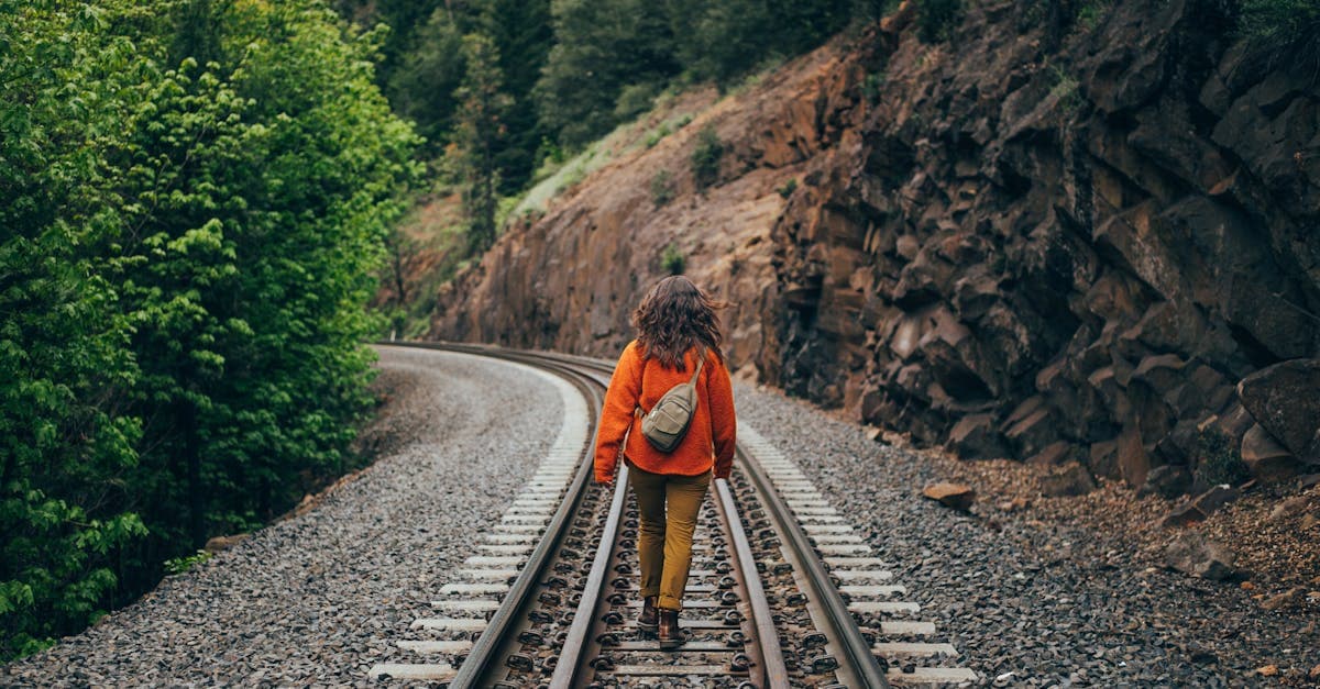 Woman walking along a railroad track through lush Northern California scenery, embracing solo travel freedom.