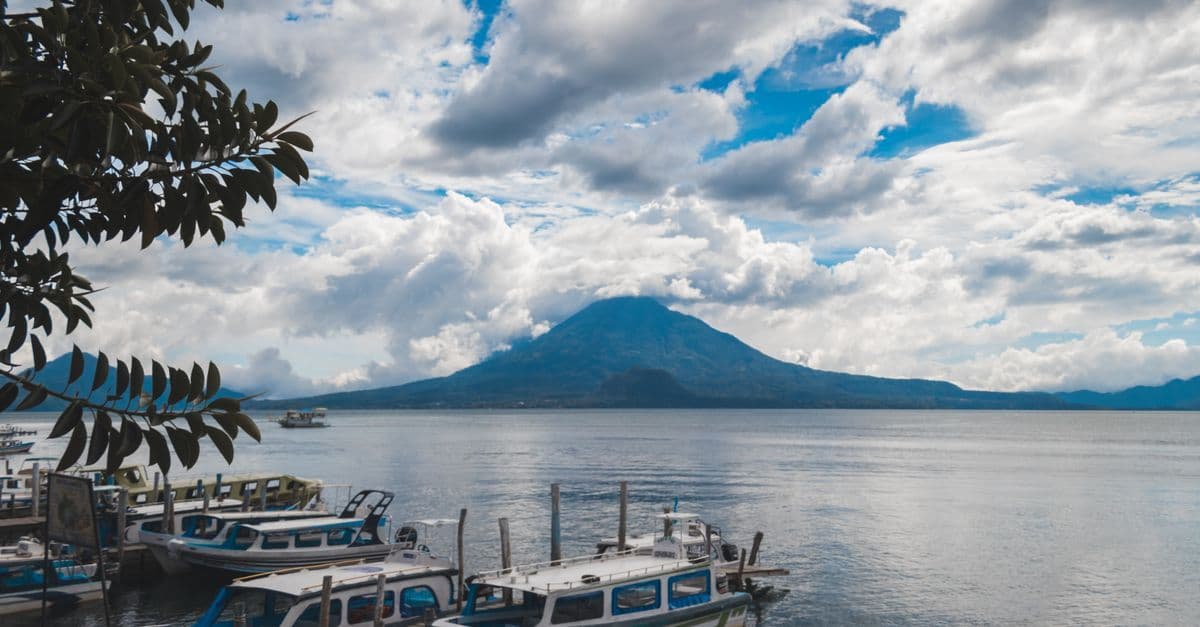 Passenger boats tie up at a dock on Lake Atitlán in Guatemala, with a volcano across the water.