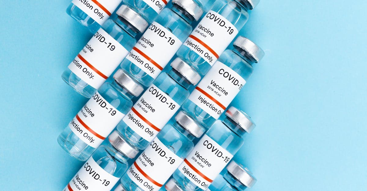 Vue du dessus de flacons de vaccins sur surface bleue, rappelant les vaccins obligatoires exigés pour voyager.