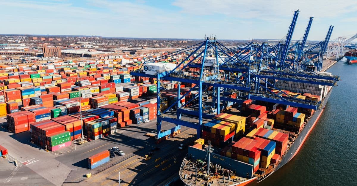 Frachtschiff mit bunten Containern im Hafen symbolisiert globale Lieferketten im Krieg USA Iran