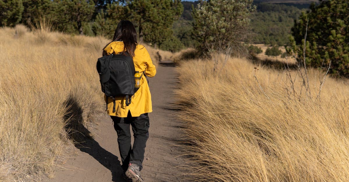 Senderista en chaqueta amarilla planificando su primer viaje solo por un sendero pintoresco en Puebla, México.